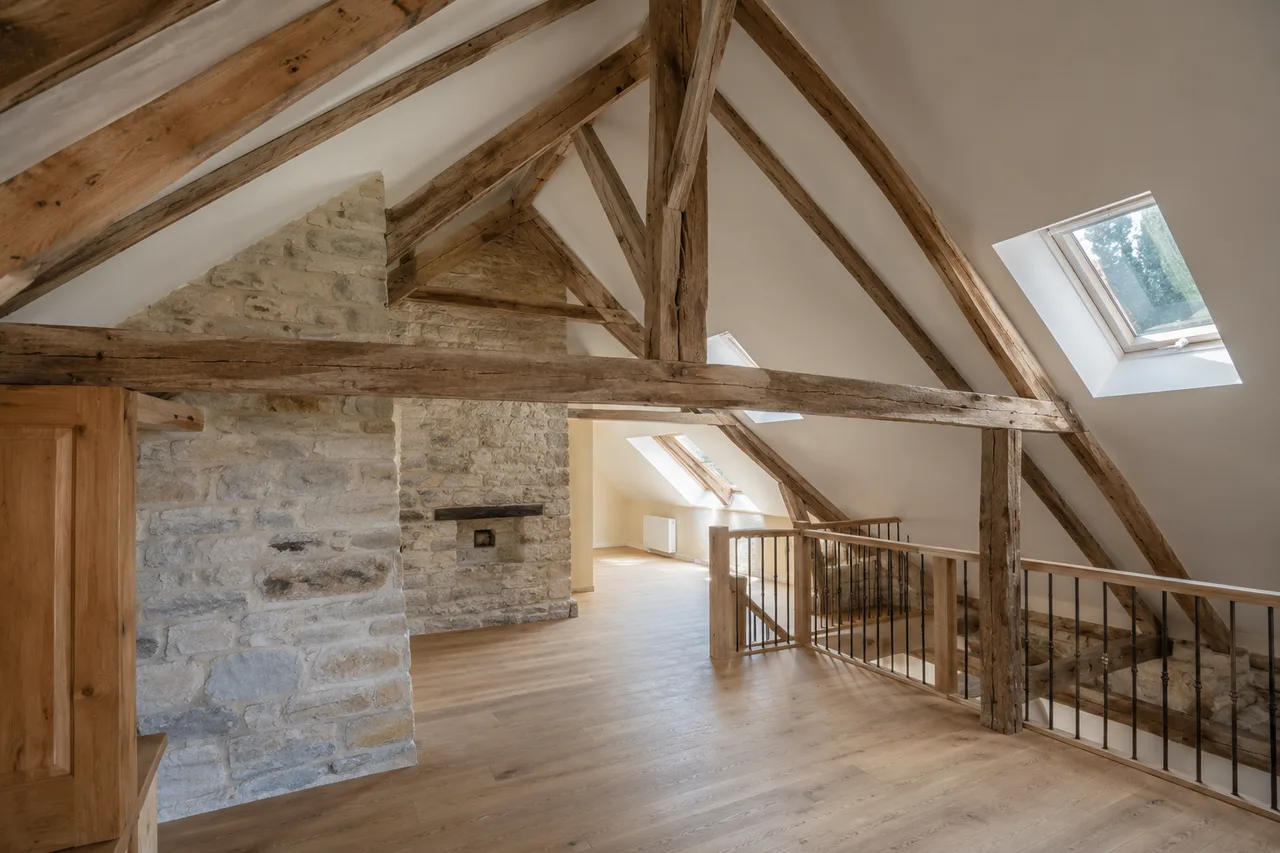 Intérieur d'une maison béarnaise rénovée par sarking, charpente bois apparente conservée et volume sous toit préservé